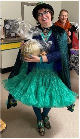 A women dressed as a peacock holds a golden pumpkin