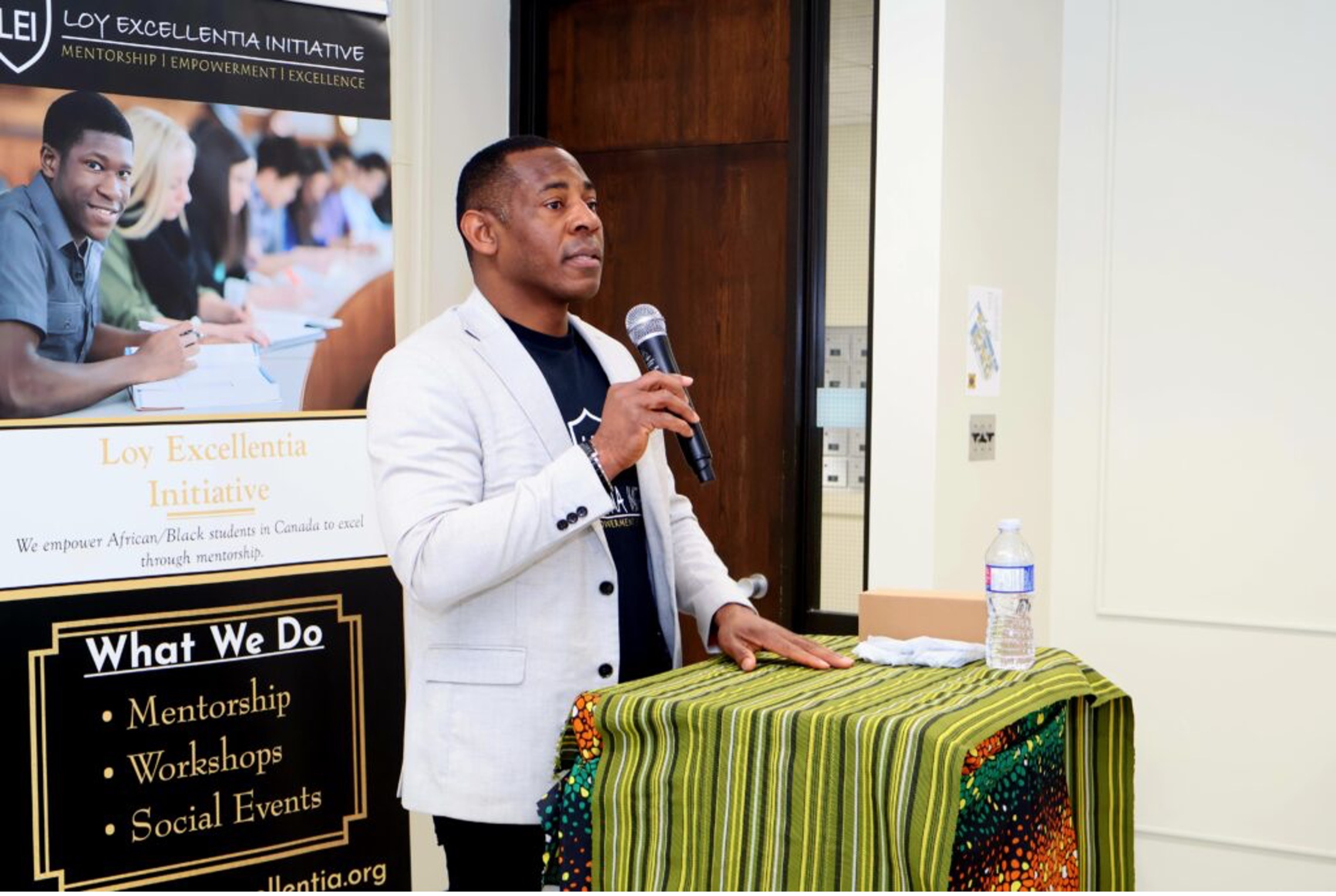 A man stands at a lectern and speaks into a microphone