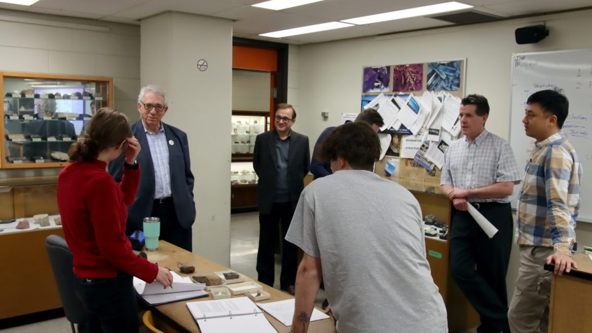 A group of people stand around a table with rock samples on it