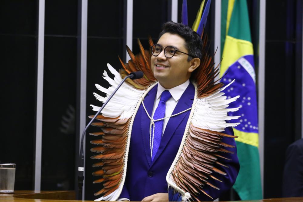 A man in a traditional headdress smiles.