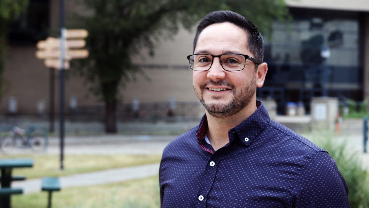 A man in glasses smiles in the BU courtyard.