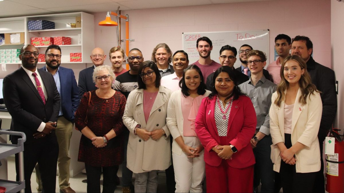 A large group of people stand in a laboratory with pink walls