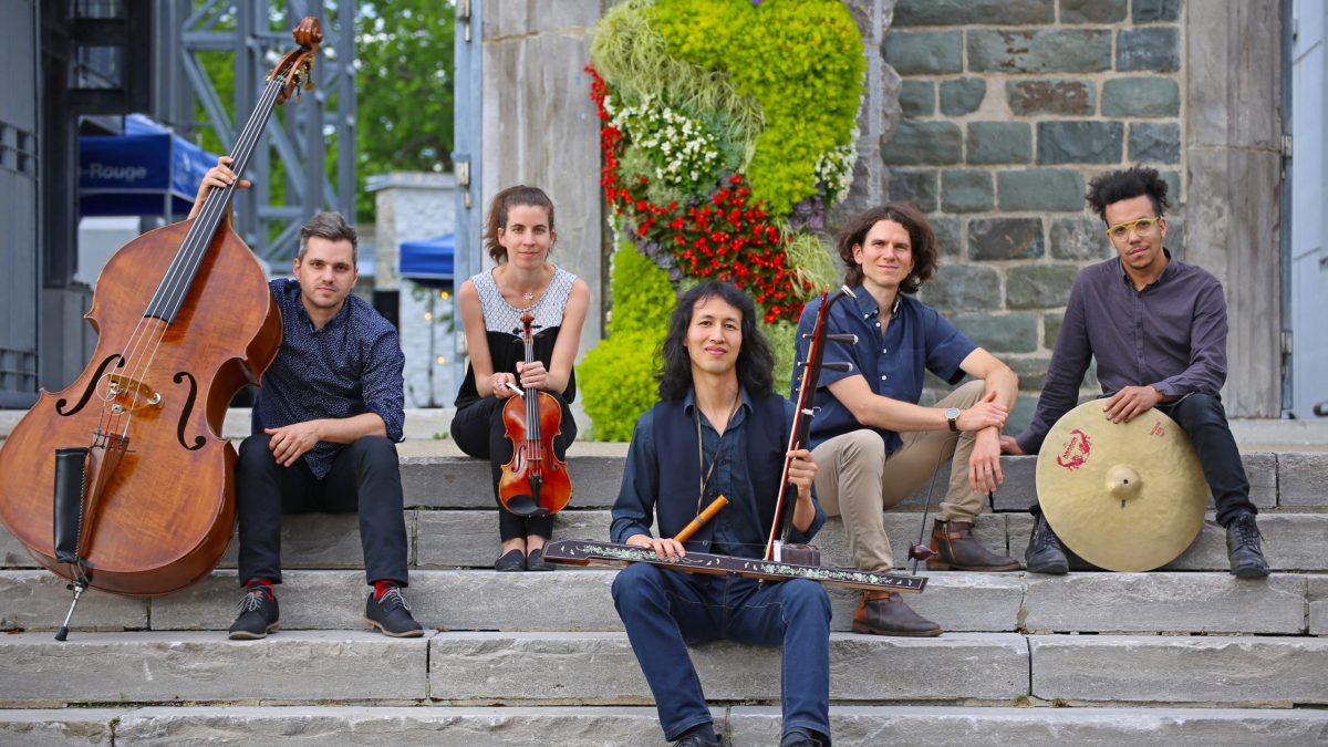 A group of musicians sit on steps with their instruments.