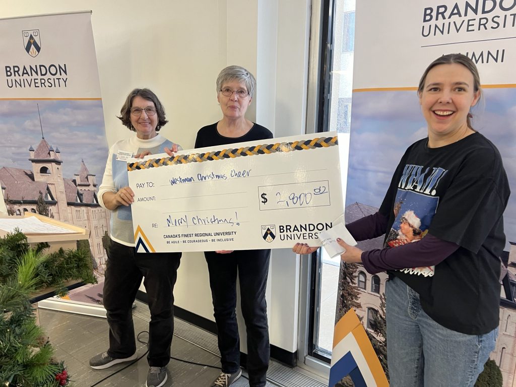 Three women pose with an oversize novelty cheque.