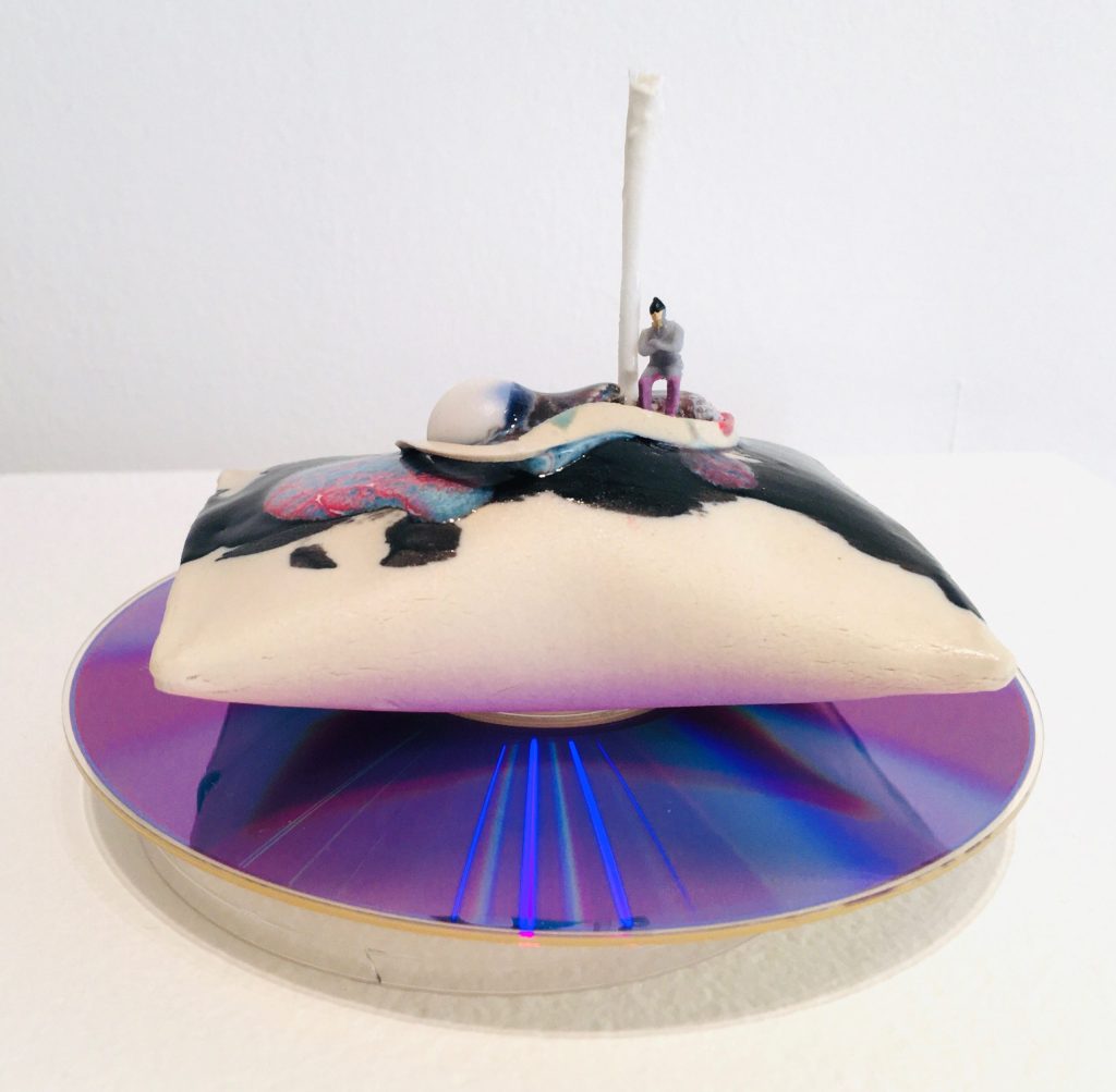 A small figure stands on top of a pillow