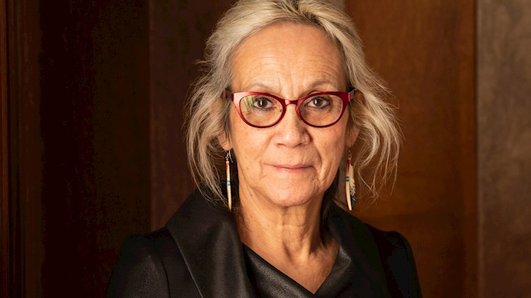 Head and shoulders formal portrait of a woman with glasses and medium-length hair.