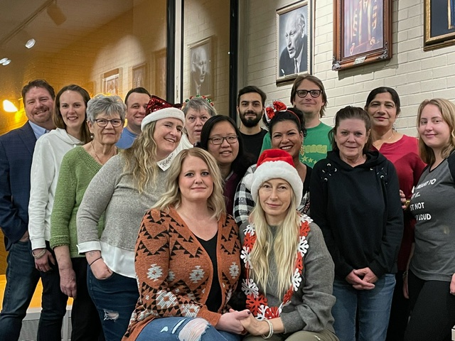 A group of people pose for a photo. Some of them are wearing Santa hats