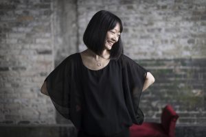 A woman smiles and looks to the side as she holds her hands on her hips