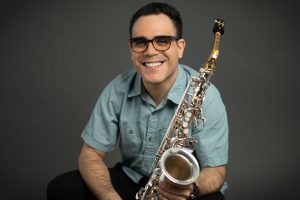 A man poses with a saxophone.