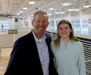 A man and a young woman smile while posing in the BU gym.