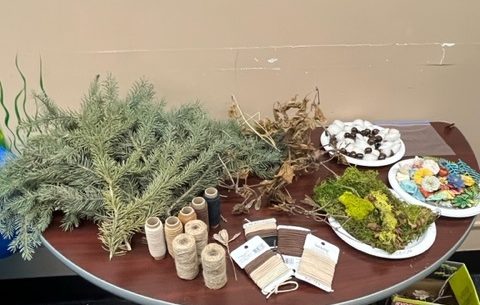 pine branches, leaves and string are arranged on a table