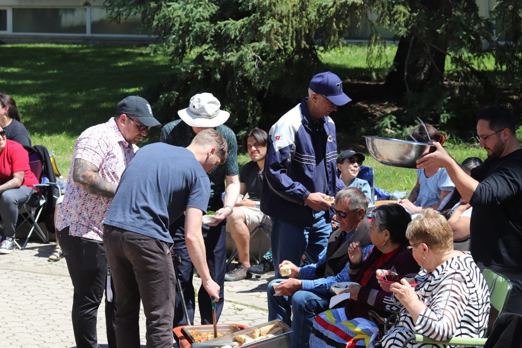 A group of men serve food to three women