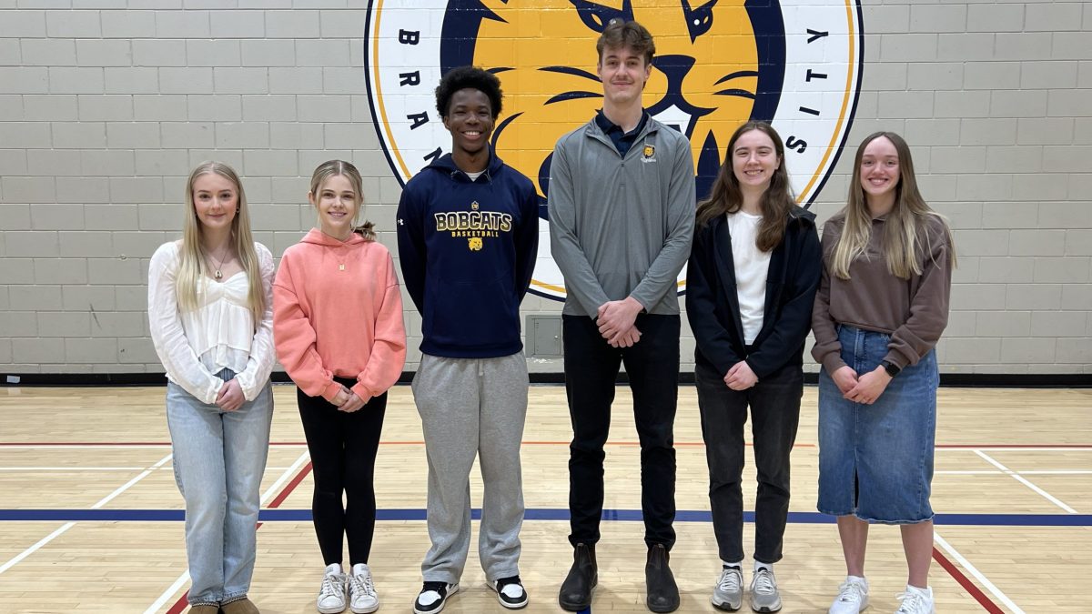 A group of students stand together in a gym, with the BU Bobcats logo behind them.