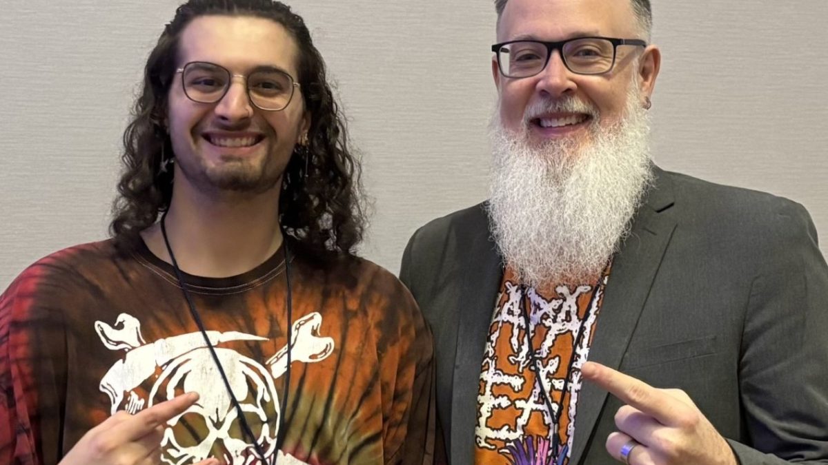 Two men in bright shirts make the "rock horns" hand gesture