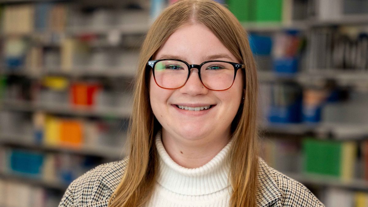 A woman in a library smiles