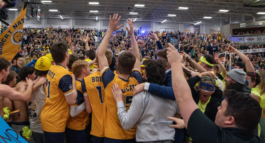 A group of athletes celebrate in front of a crowd.