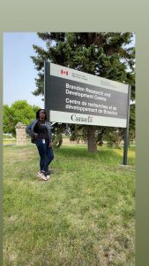 A woman poses in front of a large government sign that says Agriculture and Agri-Food Canada in both English and French.