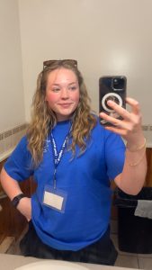 A woman with a name badge on a lanyard takes a selfie.
