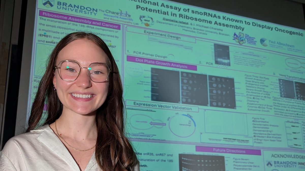 A woman smiles posing next to a research poster