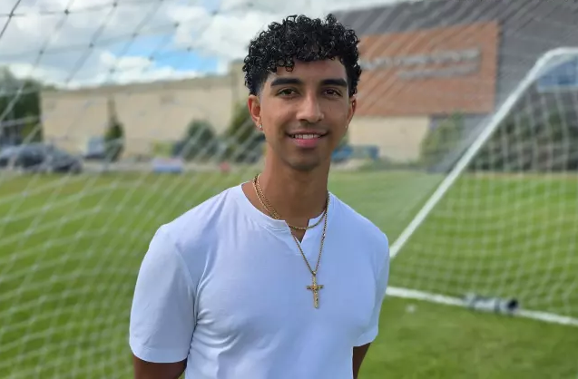 A man smiles on a soccer field