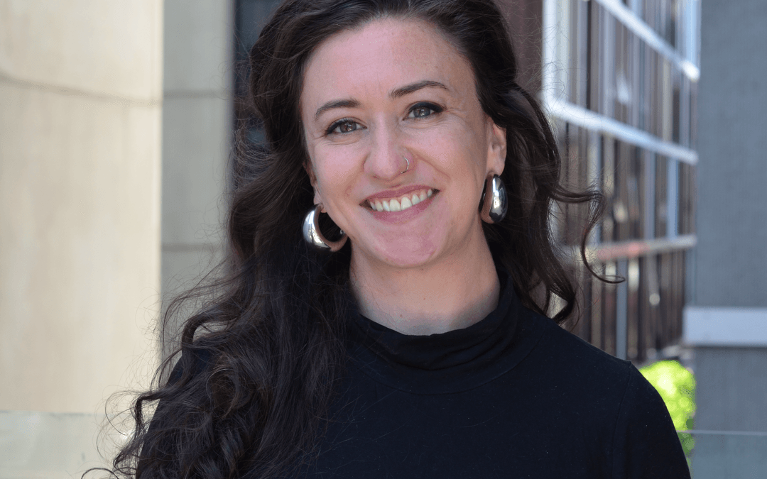 A woman poses in an academic background.