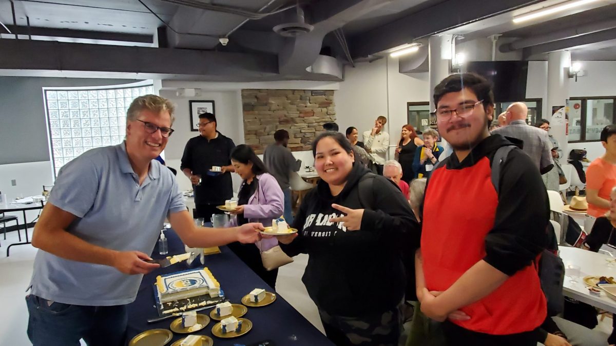 A man leans over a table to present a slice of cake.