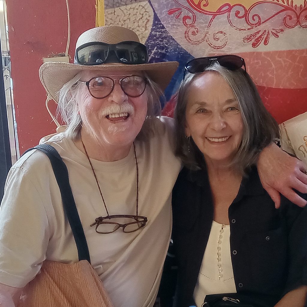 An older couple with with arms around each other.