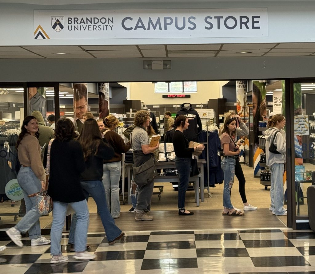 Several people stand in line at the Campus Store while others enter.