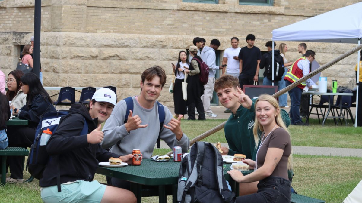 A group of people wave while seated at a table