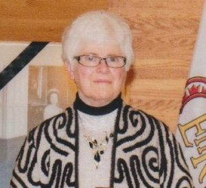 Portrait of a woman standing in front of a wood panel backdrop.