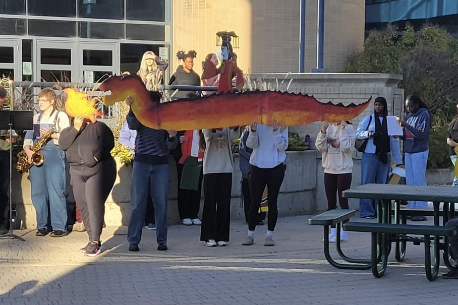 A group of people hold up a puppet of a Brandon breathing fire