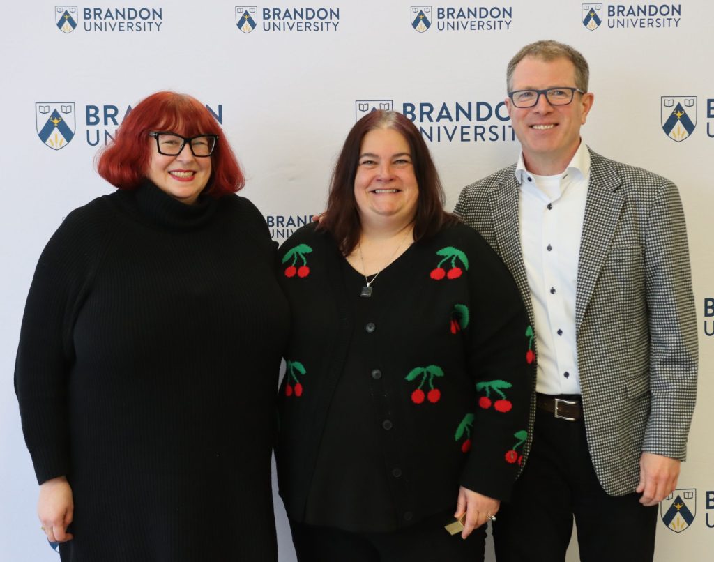 Two women pose with a man to their left