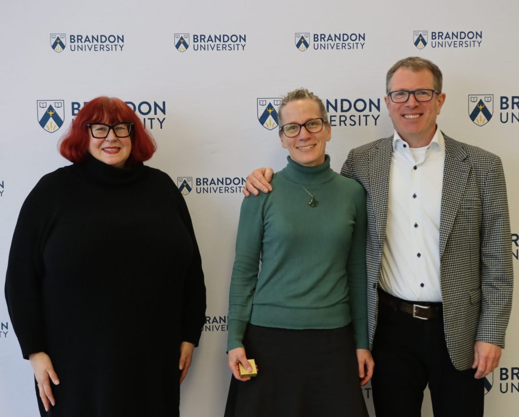 Two women pose with a man to their left