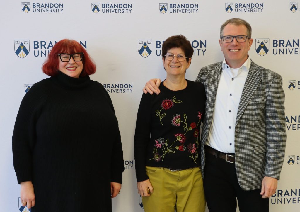 Two women pose with a man to their left