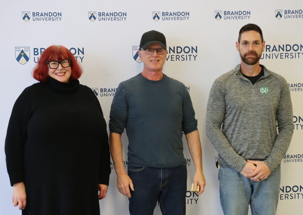 A women poses with two men to her left