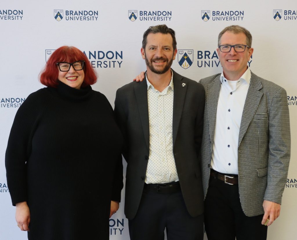 Two men pose with a woman to their right
