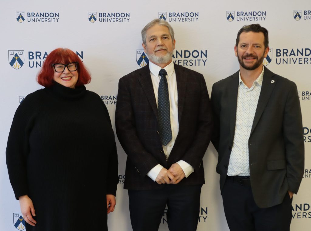 A woman poses with two men to her left