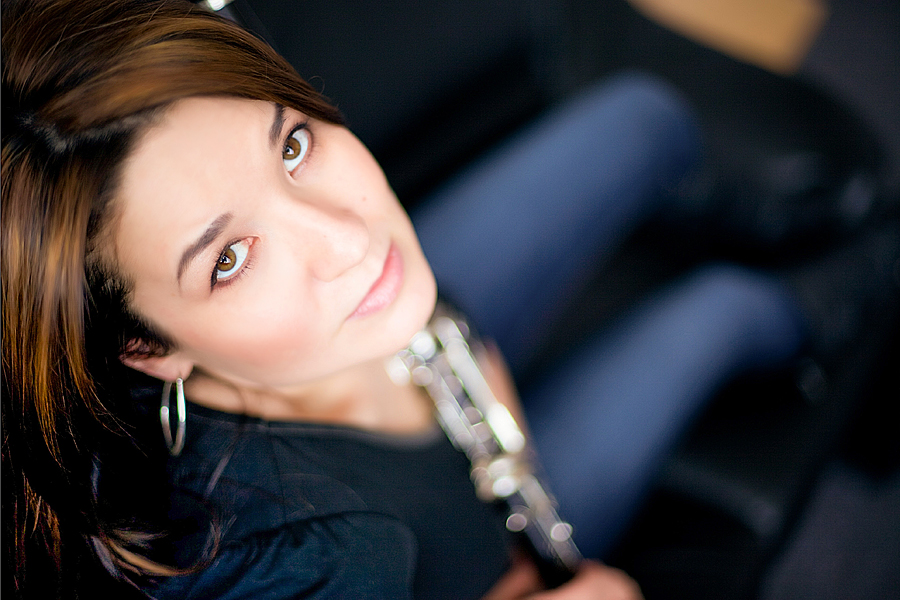 A woman holding a clarinet looks up