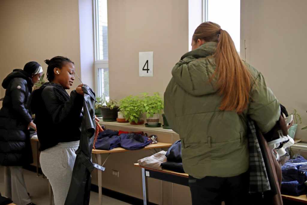 Two young women browse through racks of clothing.