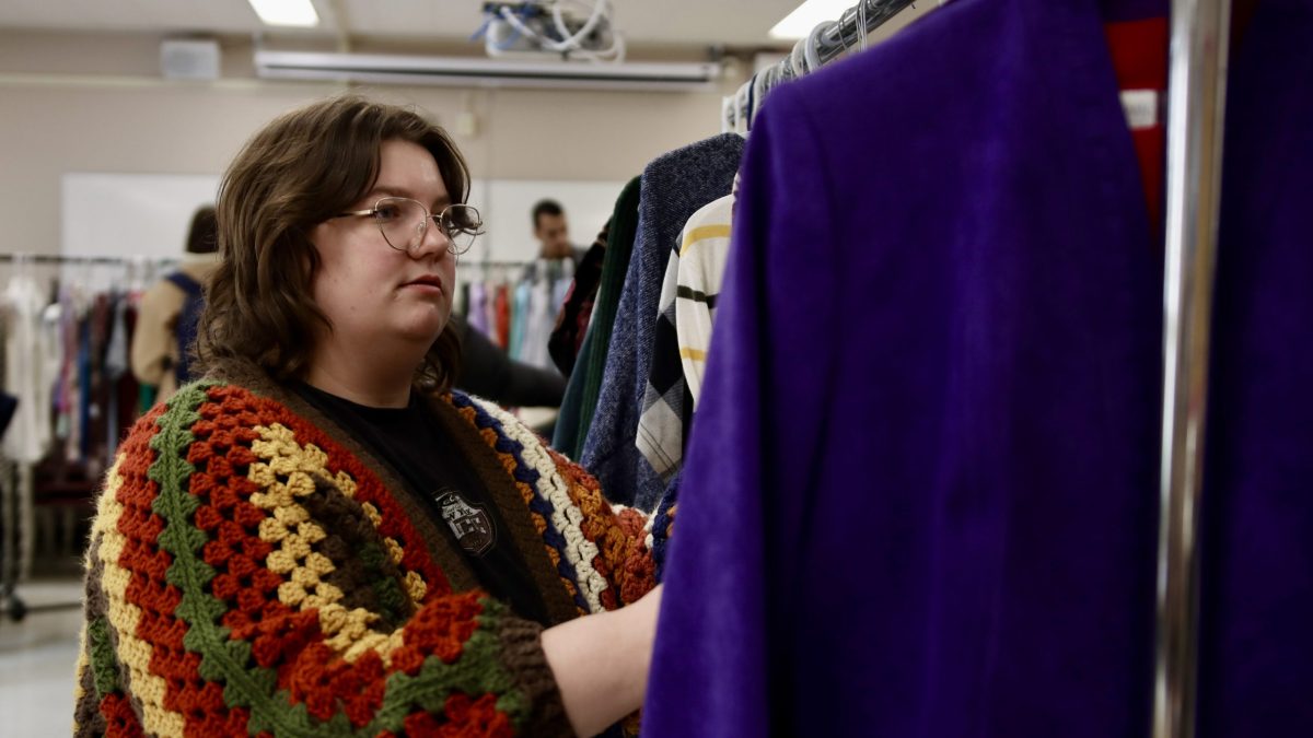 A young woman browses through racks of clothing.