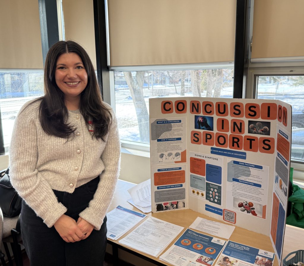 A woman poses next to a display about concussions in sports.