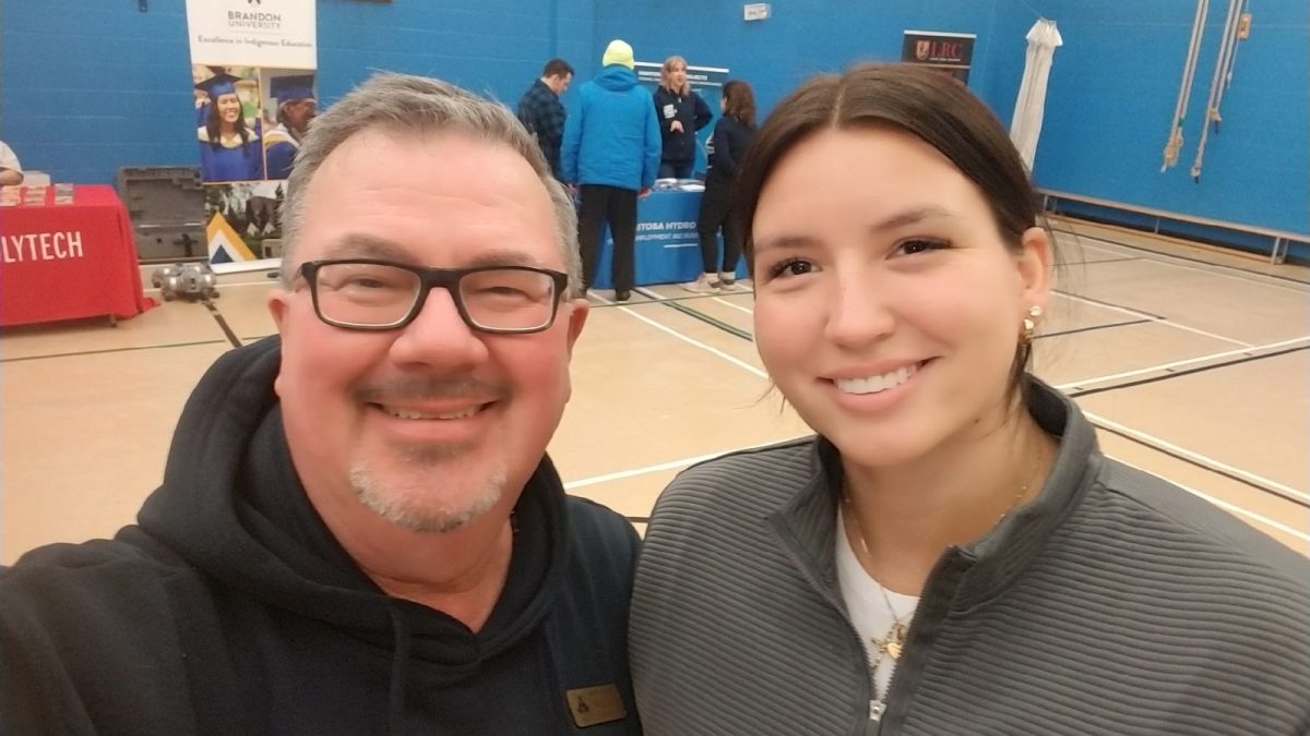 A man and a woman take a selfie in a school gym.