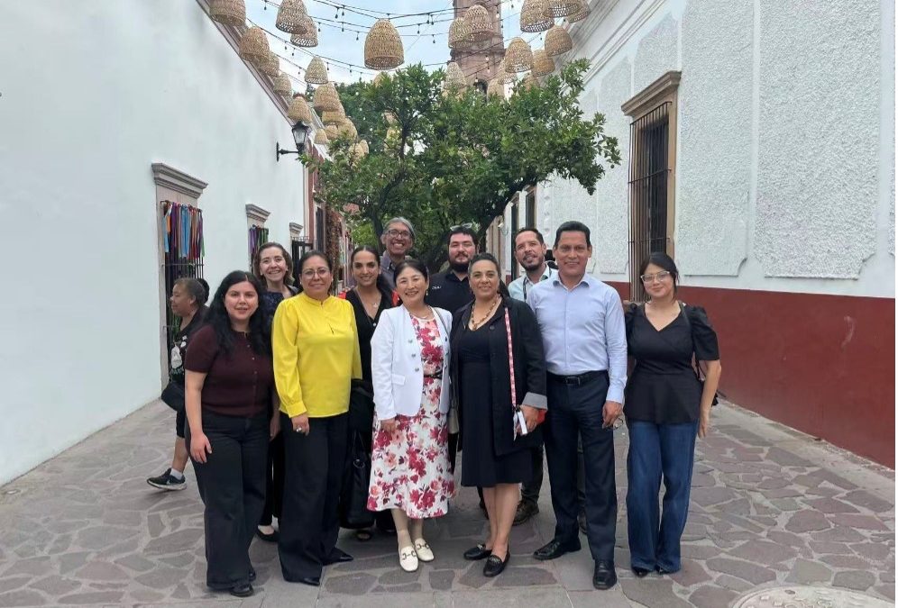 A group of people stand in an alley in front of a tree
