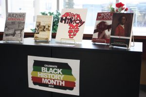 A book case displays a Black History Month sign, with a number of books on top.