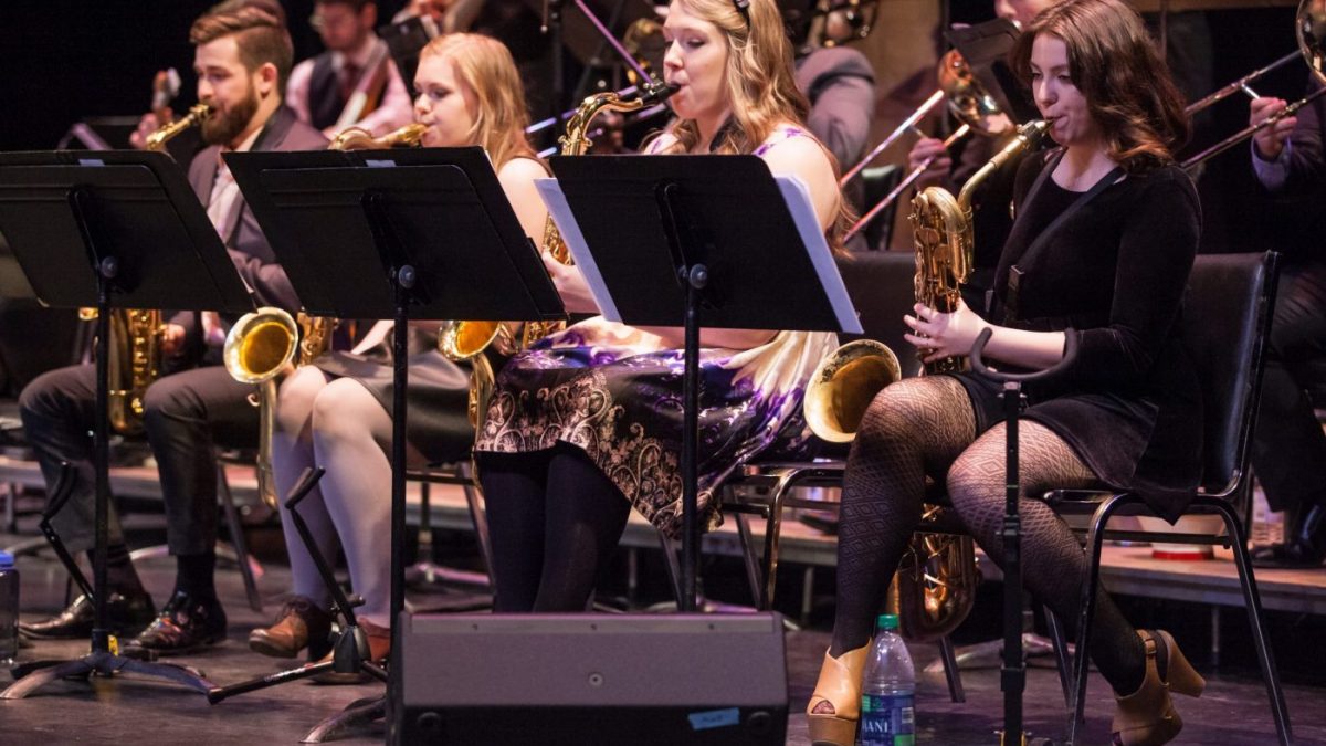 Four students play saxophone while seated at music stands