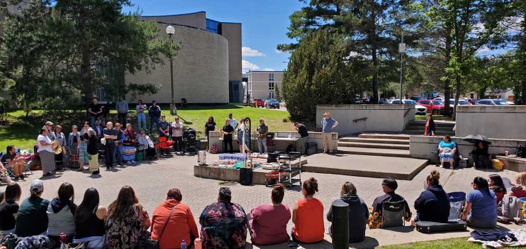 A large crowd sits in a circle at an amphitheatre