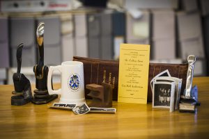Several itesm, including stamps, a coffee cup, a book and photographs sit on a table