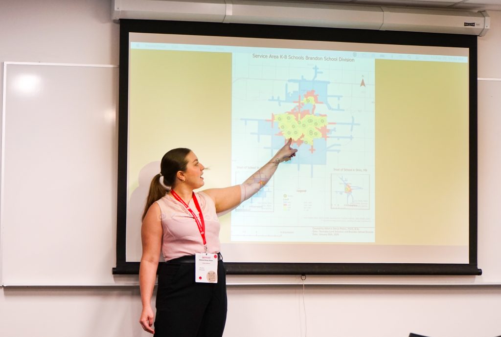 A student gestures at a city map that is projected on the screen behind her.