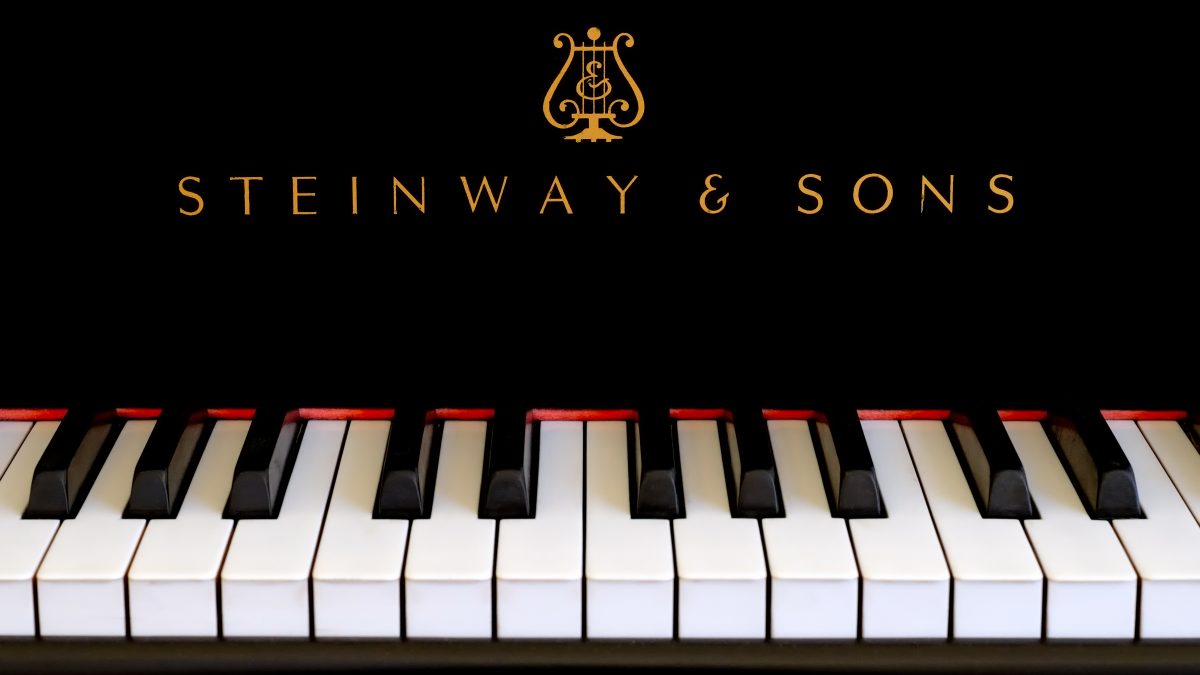 Steinway piano logo close up. Classic gold lettering above ivory piano keys.