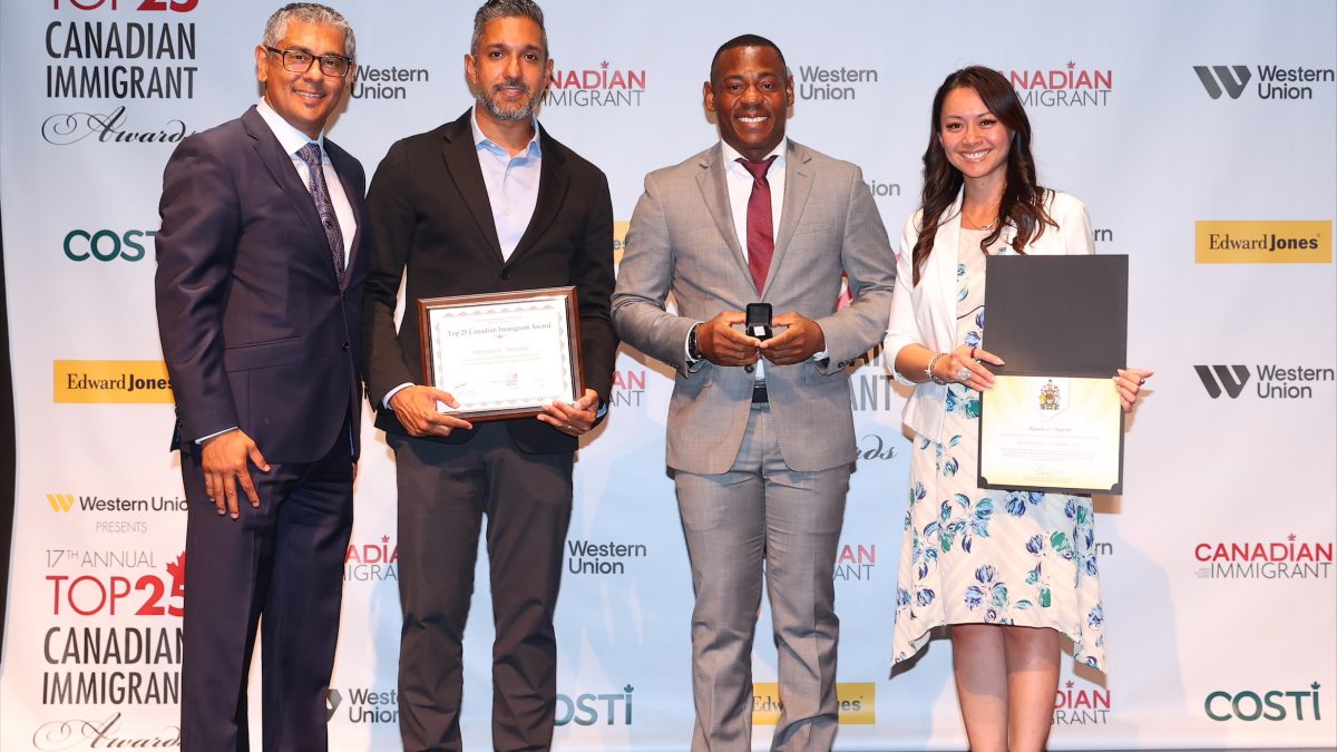 A group of four people on a stage, holding award certificates.